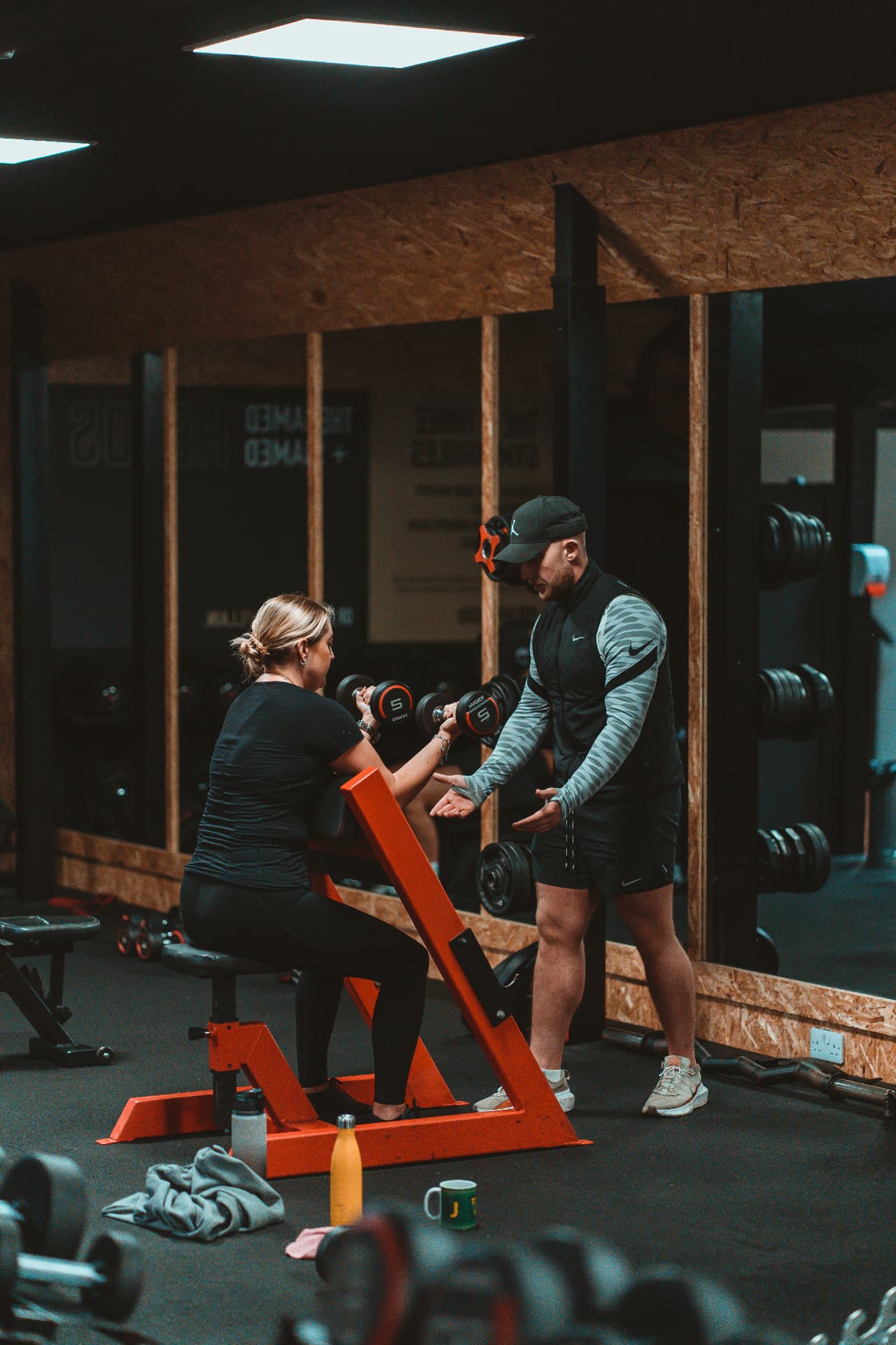 Personal trainer coaching a member through dumbbell presses at Heros