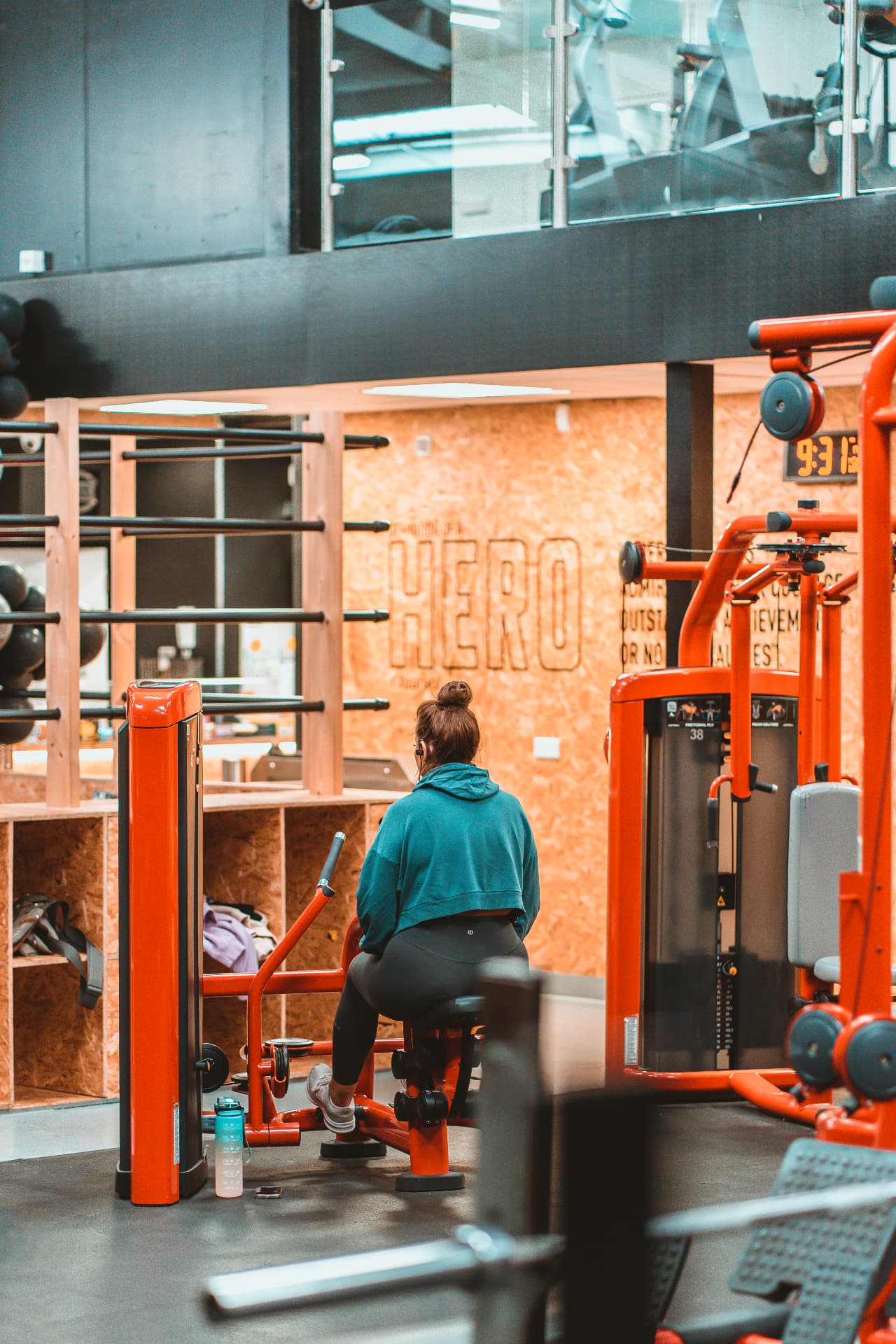 Member using a resistance machine in front of the 'Definition of a Hero' wall